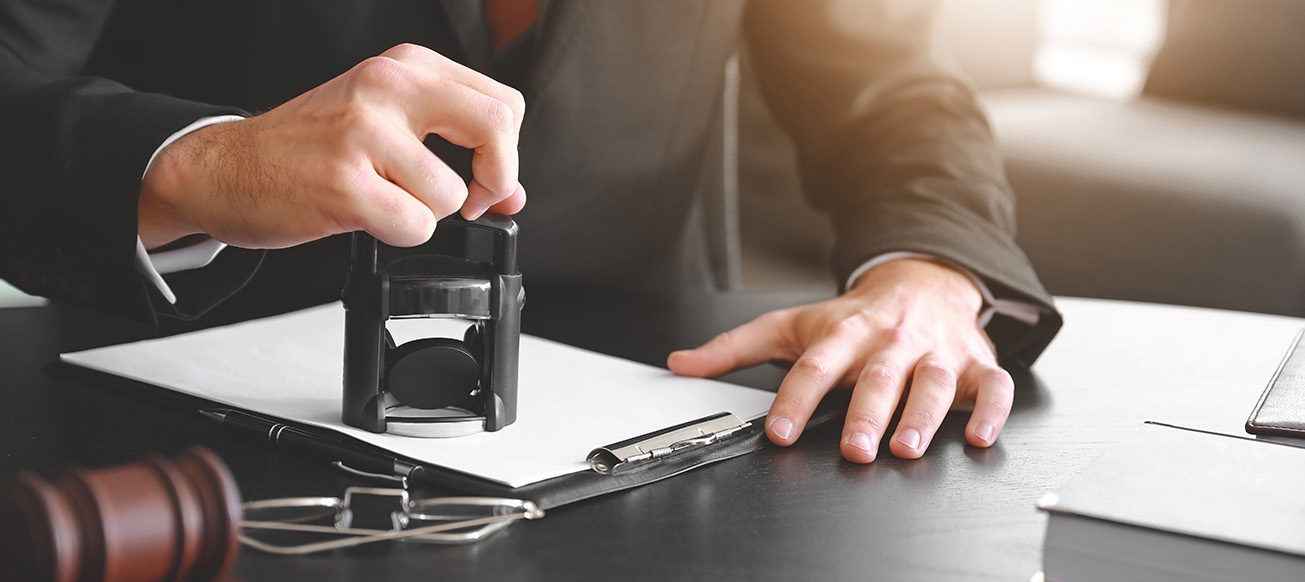 male lawyer at a desk stamping a document on a desk; Broward county Power of Attorney Lawyer concept image