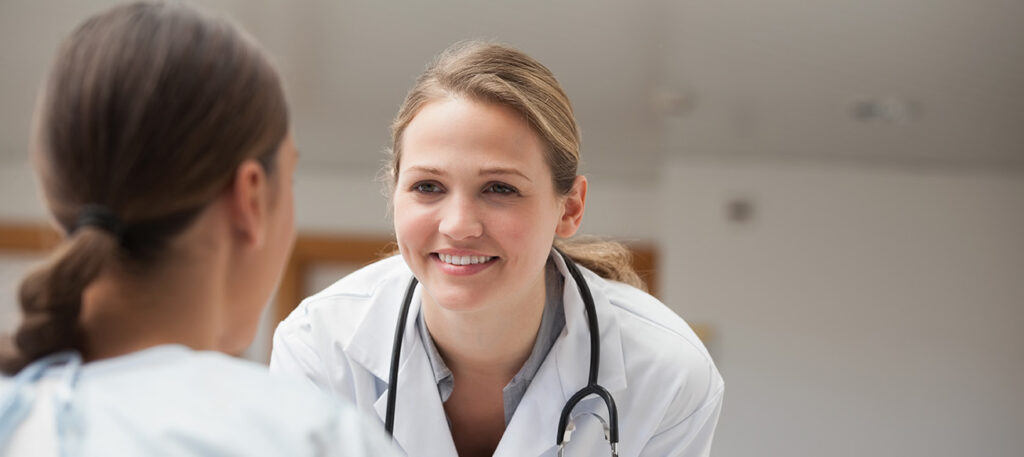 A smiling attractive female doctor speaking with a female patient in the exam room; Broward county Advance Healthcare Directive Lawyer concept image