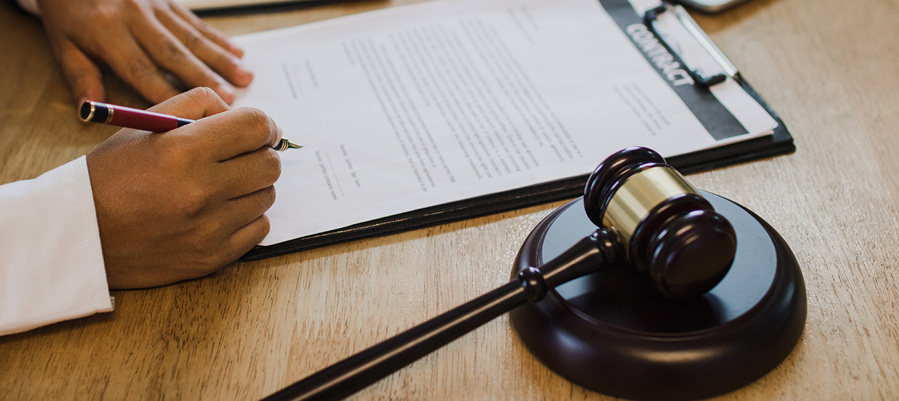 client and attorney are signing a trust with a justice hammer on the table; Broward County Trust Lawyer concept image